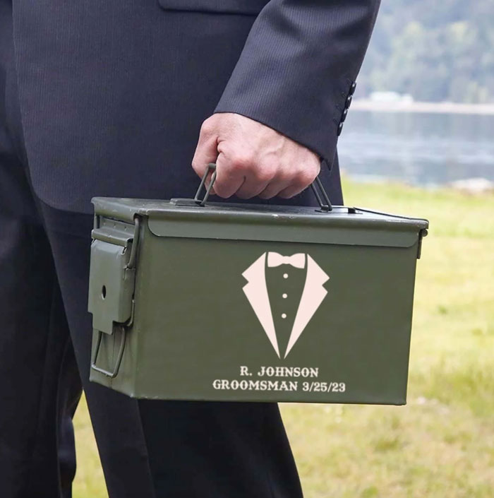 man in suit carrying an engraved ammo can