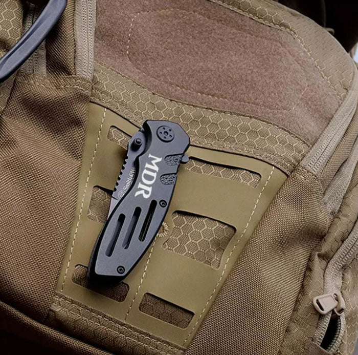 smith and wesson extreme ops engraved knife sitting on a backpack
