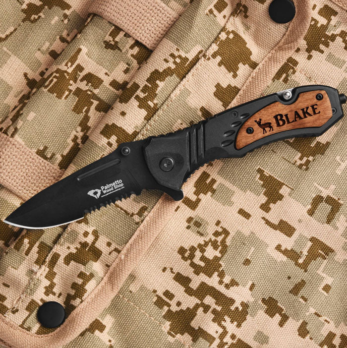 black engraved pocket knife sitting on a digi camo bag
