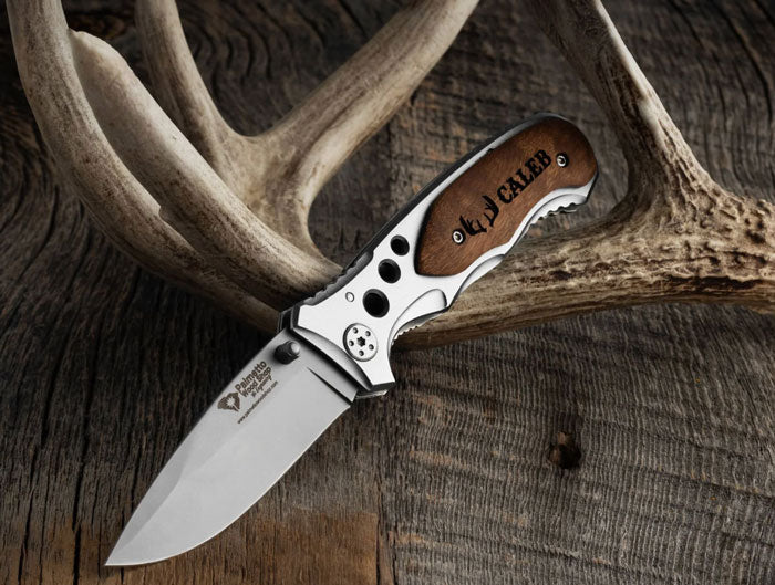 Folding knife with wooden handle and engraved text on antlers