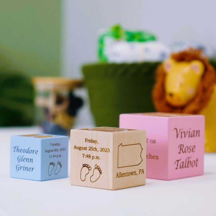 three different size baby blocks in blue, natural, and pink