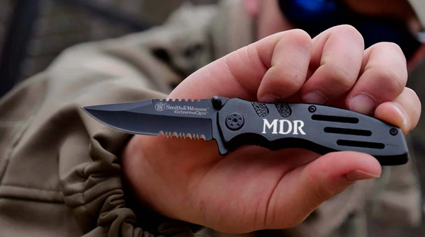 man holding a black serrated blade pocket knife