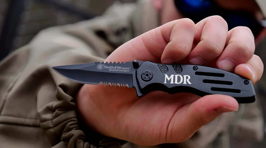 man holding a black serrated blade pocket knife