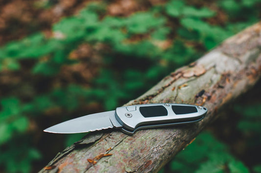 A pocket knife on a log in a forest