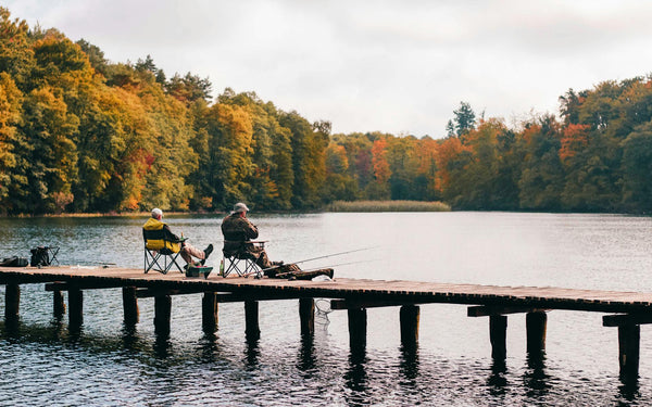 two fishermen fishing by a lake