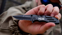man holding an engraved Smith and Wesson black pocket knife