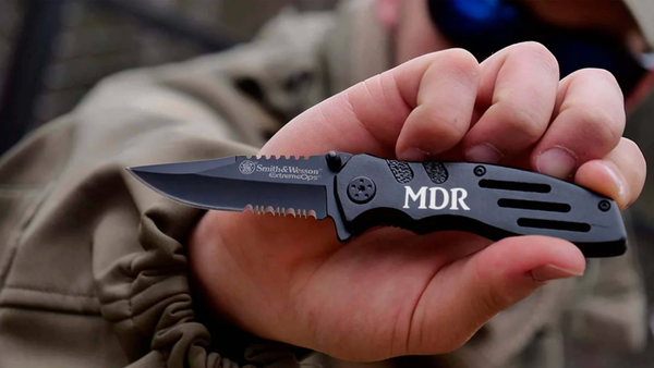 man holding an engraved Smith and Wesson black pocket knife